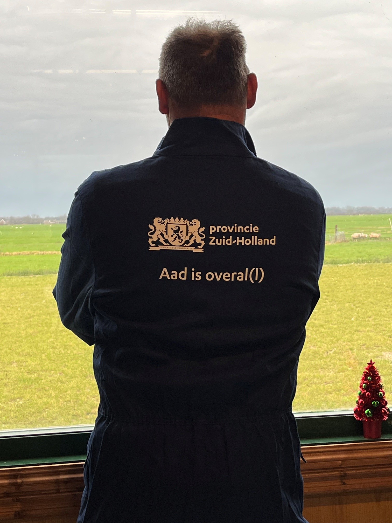 Aad Straathof in een overall met de tekst "Aad is overal(l)"